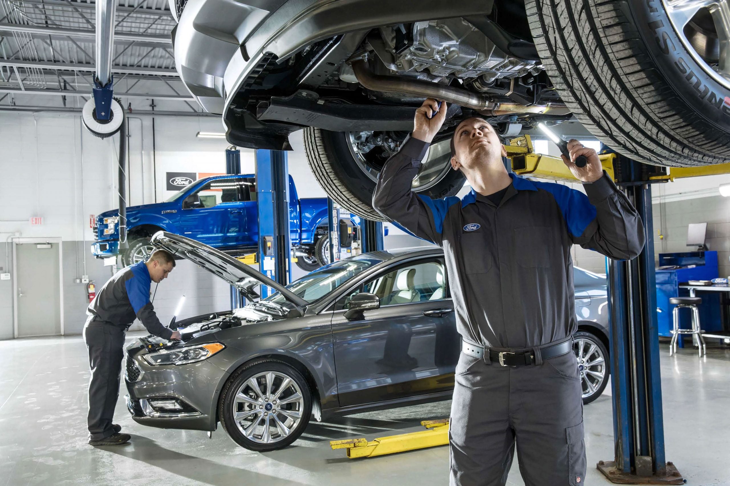 Two men repairing a vehicle in a garage, focused on their work.