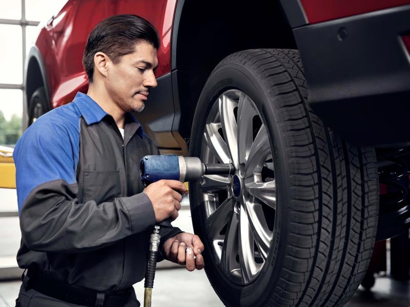 A man repairs a tire in a garage, surrounded by tools and equipment, focused on his task.