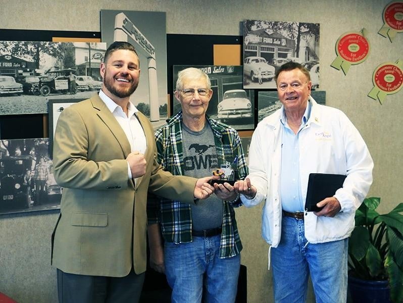 Three men stand side by side, each holding a plaque, smiling at the camera in a celebratory setting.