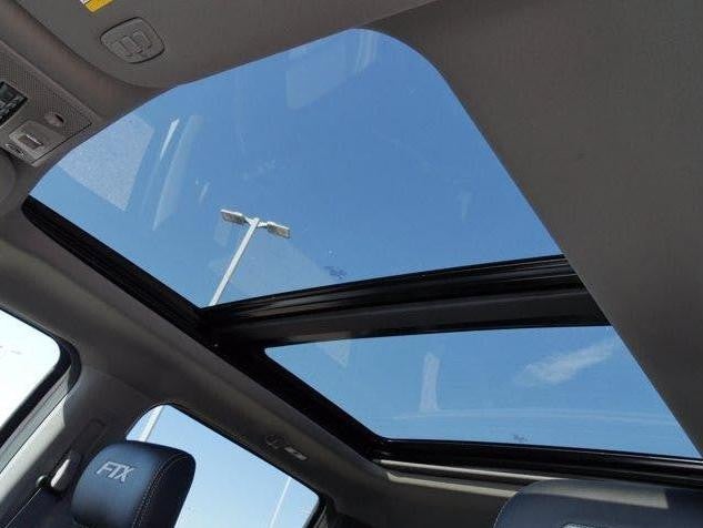 Sunroof view from the back seat of a car, showcasing the open sky above.