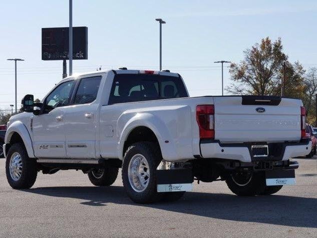 Back view of a white truck parked in a lot, showcasing its tailgate and rear lights.