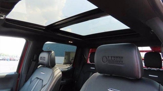 Open sunroof in the back of a car, allowing sunlight to enter the interior.