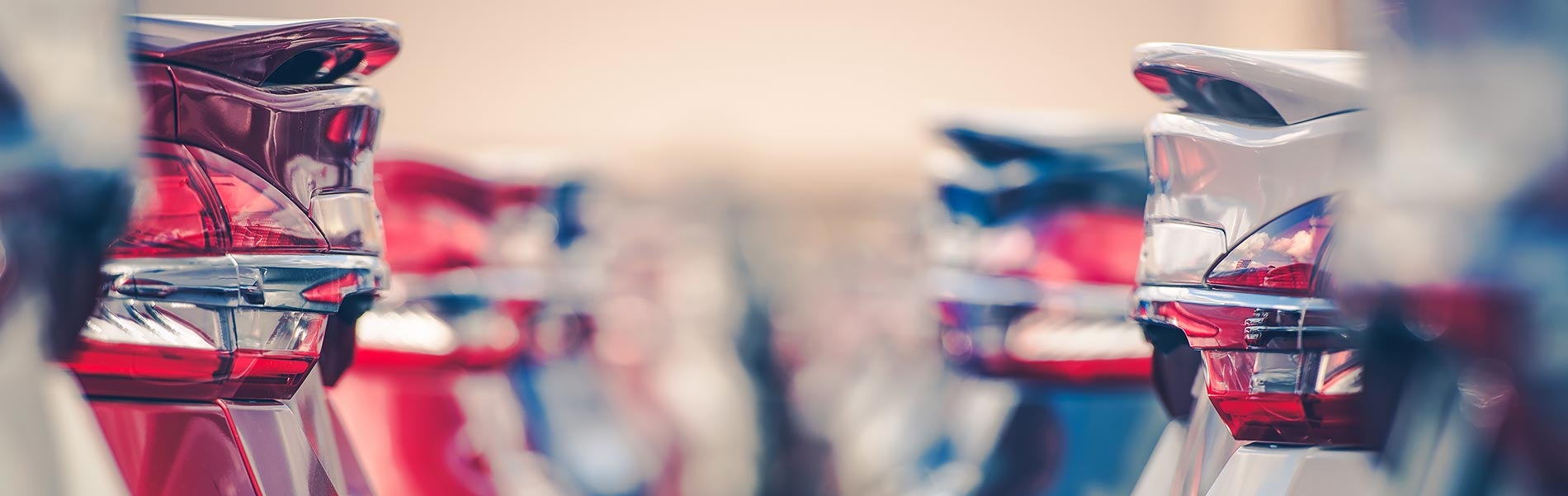 A row of red, white, and blue cars parked side by side on a sunny day.